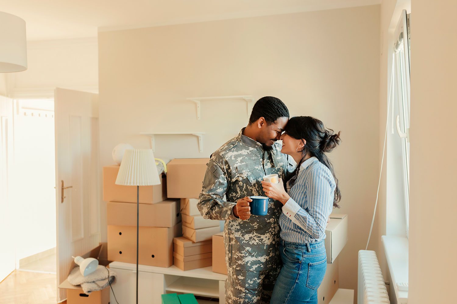 Featured image for VA Home Loans, showing a male Servicemember and his wife moving into their new home